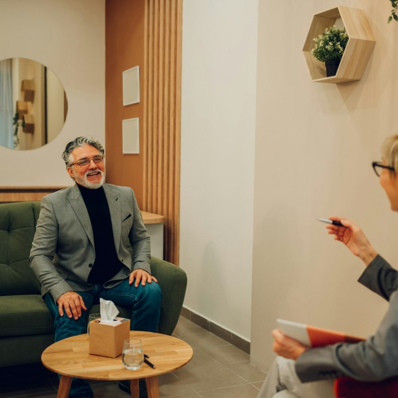 A cheerful mature man is solving problems with a psychotherapist